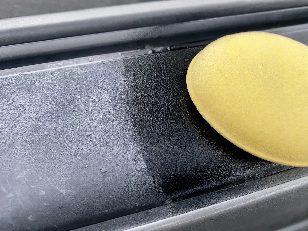 Close-up of faded plastic trim being restored to a deep, even black finish with an applicator pad — Prestige Marine & Auto Care in Seattle, WA..replace